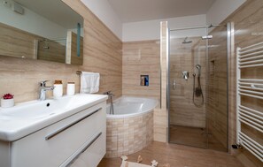 Features a sleek vanity, bathtub, and glass-enclosed shower area.