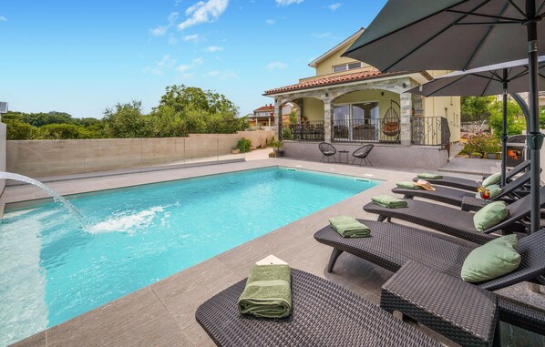 Relax by the serene pool, surrounded by lush greenery and comfortable lounge seating.