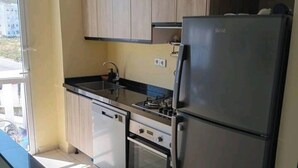 Een moderne keuken met houten kastjes, een roestvrijstalen koelkast, een gasfornuis en een inbouwoven.