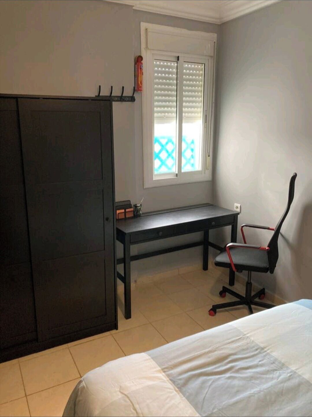 Ein Schlafzimmer mit einem Bett, einem Schreibtisch, einem Stuhl und einem Kleiderschrank.