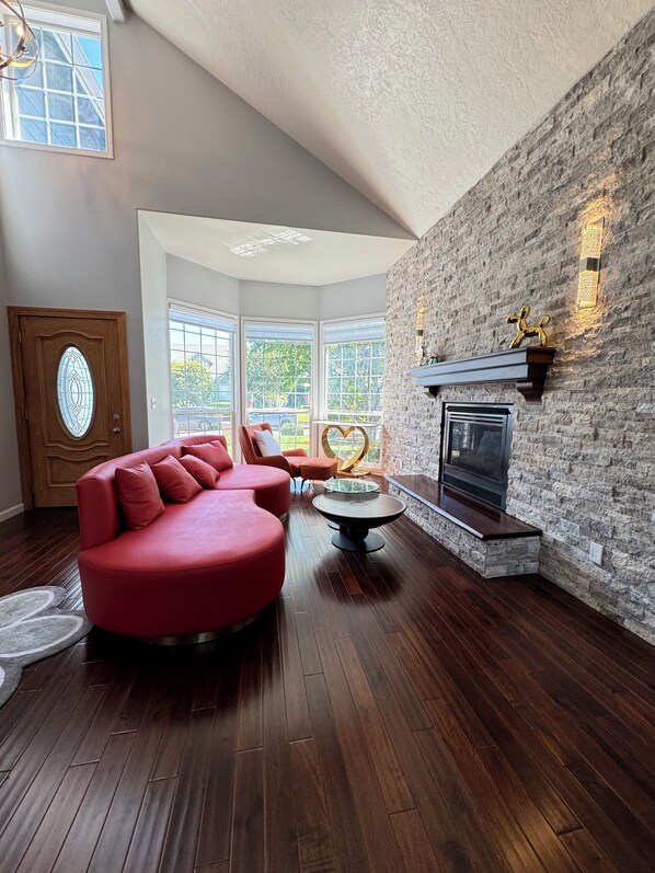 A modern living room with a red sectional sofa, a round coffee table, and a stone fireplace. - Modern Vacation Home w/ hottub, pool table. Next to lovely park. Shopping nearby (Albany)