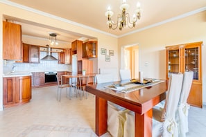 A spacious kitchen with wooden cabinets, a dining table, and a chandelier.
