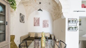 A cozy room with a stone arch, a glass table, a sofa, and a decorative vase. - Terrazza 42 by Wonderful Italy (Ostuni)