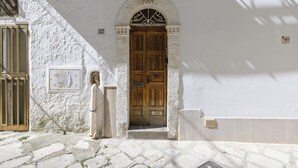 A white building with a wooden door and a statue in front. - Terrazza 42 by Wonderful Italy (Ostuni)