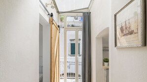 A narrow hallway with a wooden door, a glass door leading to a balcony, and a framed picture on the wall. - Terrazza 42 by Wonderful Italy (Ostuni)