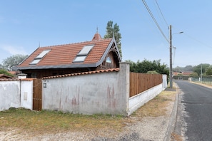 Una casa con tetto spiovente, recinzione in legno e vialetto lastricato.
