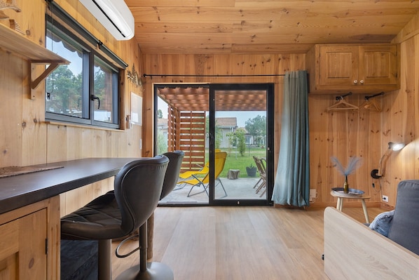 Un interior de madera con barra, asientos y un gran ventanal corredero que da a un espacio exterior.