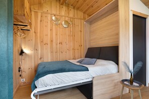 Una stanza con rivestimento in legno, un letto, un tavolino con un vaso e un lampadario a parete.