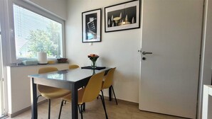 A dining area with a table, chairs, a vase of flowers, and two framed pictures on the wall. - Apartment Lončar with sea view (Krk)