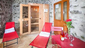 A room with two red lounge chairs, a wooden door, and a table with a bottle and glasses. - Cozy home in Privas with sauna (Privas)