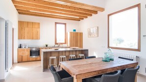 A modern kitchen with wooden cabinets, a central island with stools, and a dining table with chairs. - Finca 'Son Sec Nou' with Mountain Views, Wi-Fi and Air Conditioning (El Palmer)