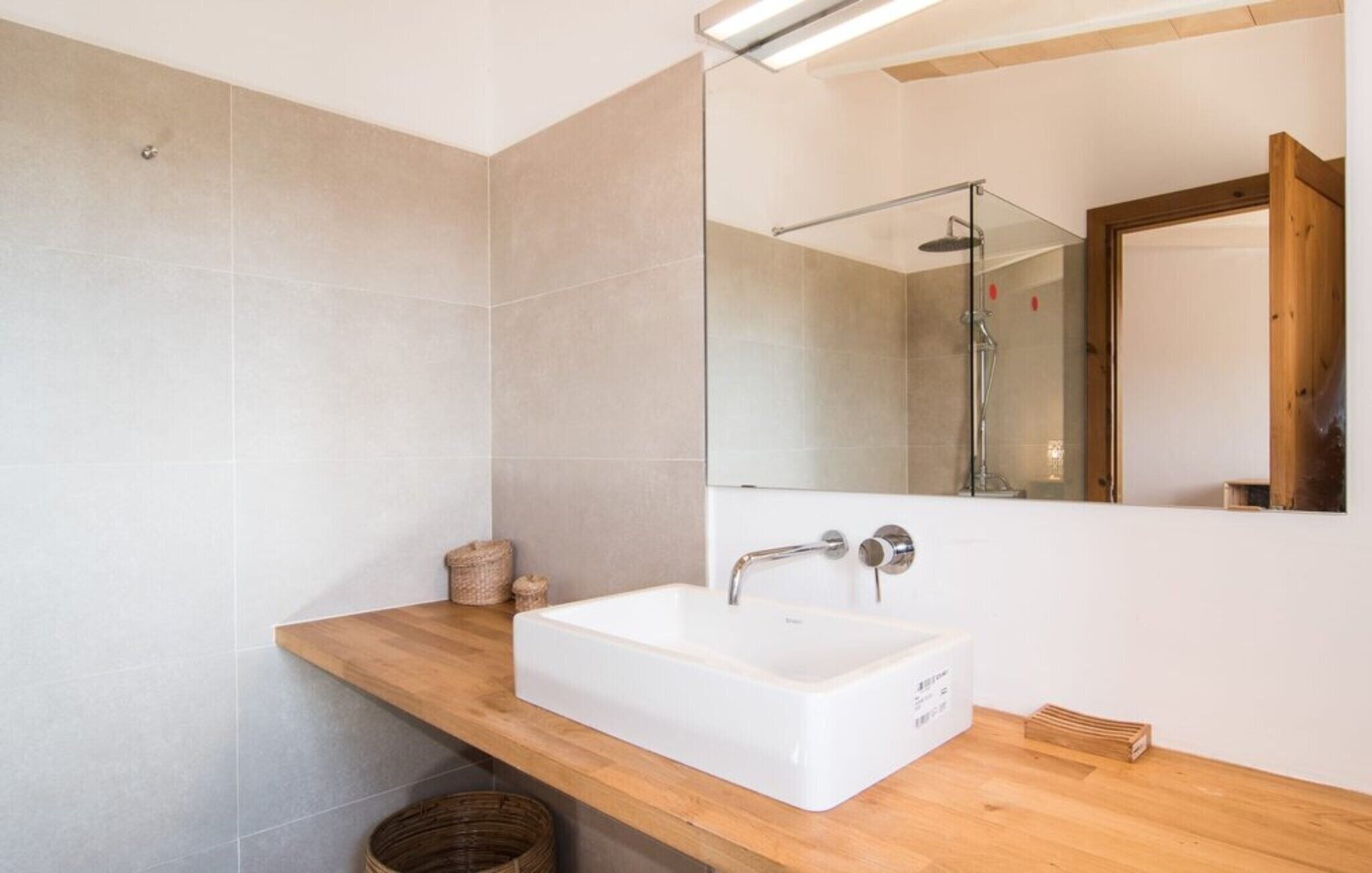A bathroom with a white sink, wooden countertop, and a glass shower enclosure.