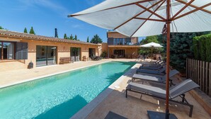 A swimming pool with lounge chairs and umbrellas, a building with a tiled roof, and a clear blue sky. - Holiday Home 'S'hort Des Frares' with Mountain View, Wi-Fi and Air Conditioning (El Palmer)