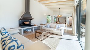 A modern living room with a fireplace, sofa, coffee table, and a view of the outdoors. - Holiday Home 'S'hort Des Frares' with Mountain View, Wi-Fi and Air Conditioning (El Palmer)