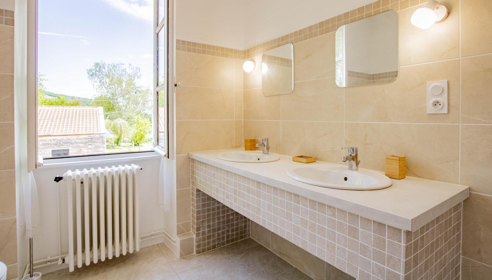 Een badkamer met twee wastafels, een raam en een radiator.