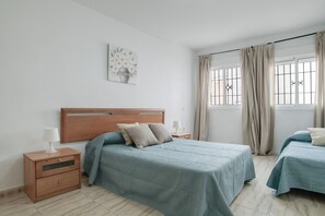 Een slaapkamer met een groot bed, twee nachtkastjes, een wandlamp en een kunstwerk aan de muur.