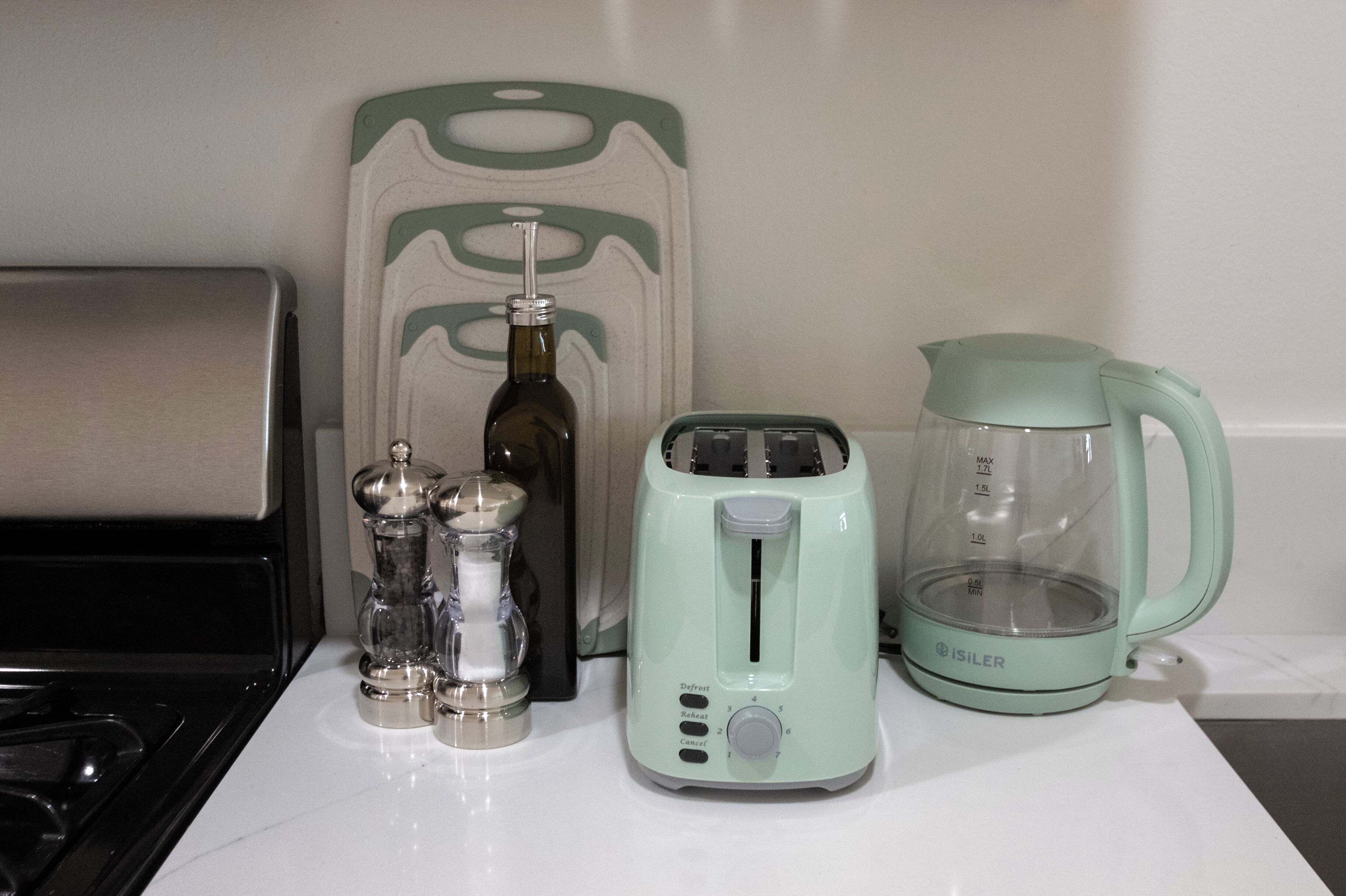 A kitchen counter with a toaster, a kettle, a salt and pepper set, and a bottle.