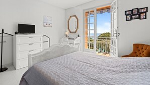 A bedroom with a bed, a dresser, a television, a mirror, and a balcony with a view. - Holiday Home 'La Belle Provence' with Sea View, Wi-Fi and Air Conditioning (Roquebrune-sur-Argens)