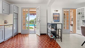 A modern kitchen with white cabinets, a built-in dishwasher, and a view of a swimming pool. - Holiday Home 'La Belle Provence' with Sea View, Wi-Fi and Air Conditioning (Roquebrune-sur-Argens)