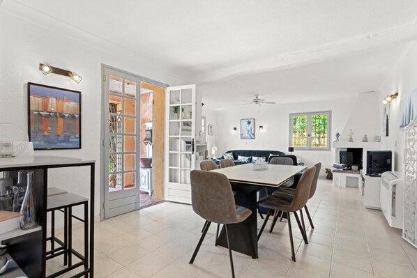 A modern kitchen with a dining area, a built-in bookshelf, and a large window.
