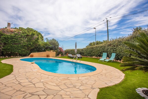 A swimming pool with stone tiles, surrounded by grass and bushes, with a clear sky above. - Holiday Home 'La Belle Provence' with Sea View, Wi-Fi and Air Conditioning (Roquebrune-sur-Argens)