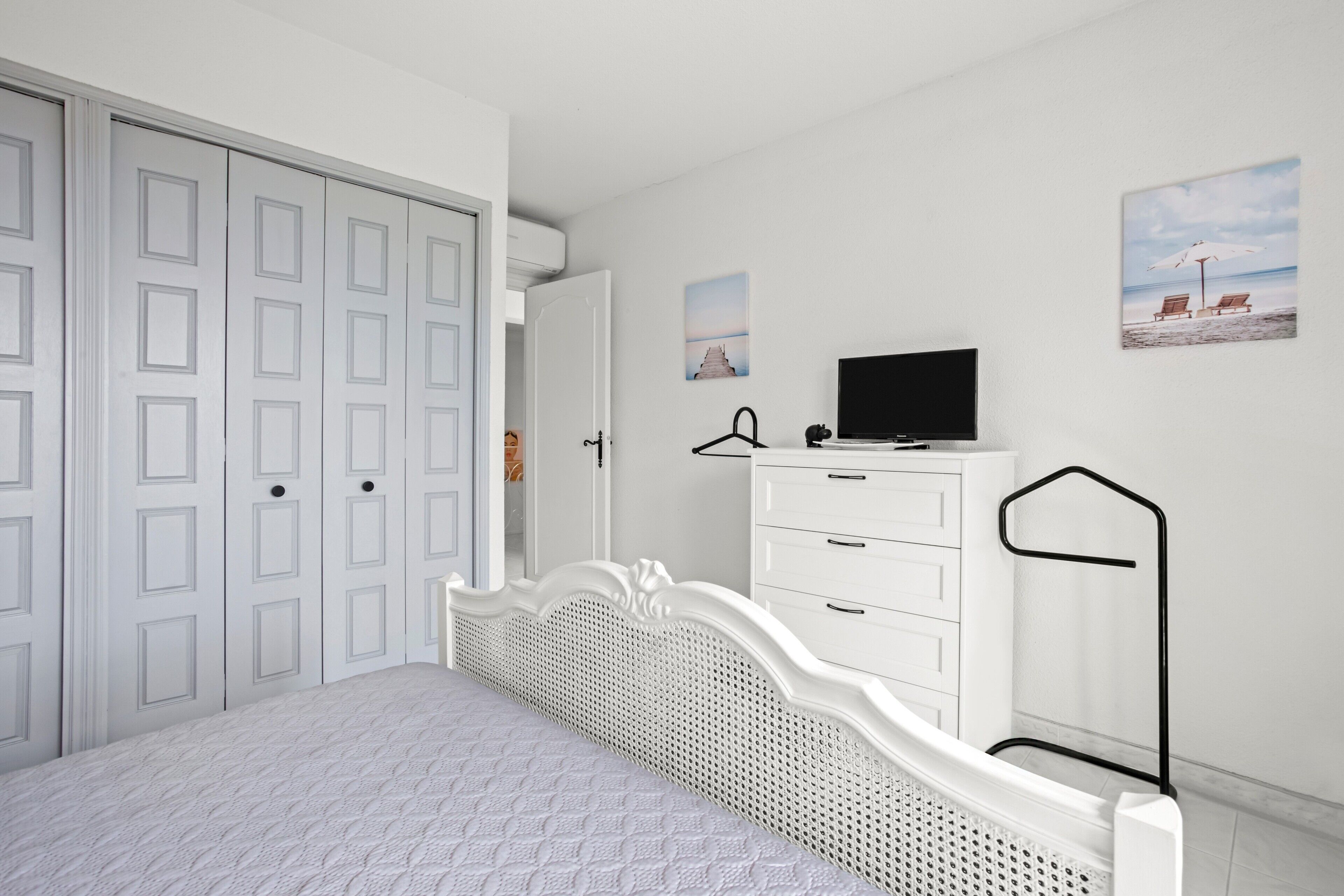Quarto com uma cama, penteadeira, televisão e armário.