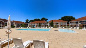 Un hotel con piscina, sillones de descanso y un cielo azul despejado.