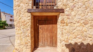 A stone building with a wooden door, a balcony with metal railings, and a clear sky.
