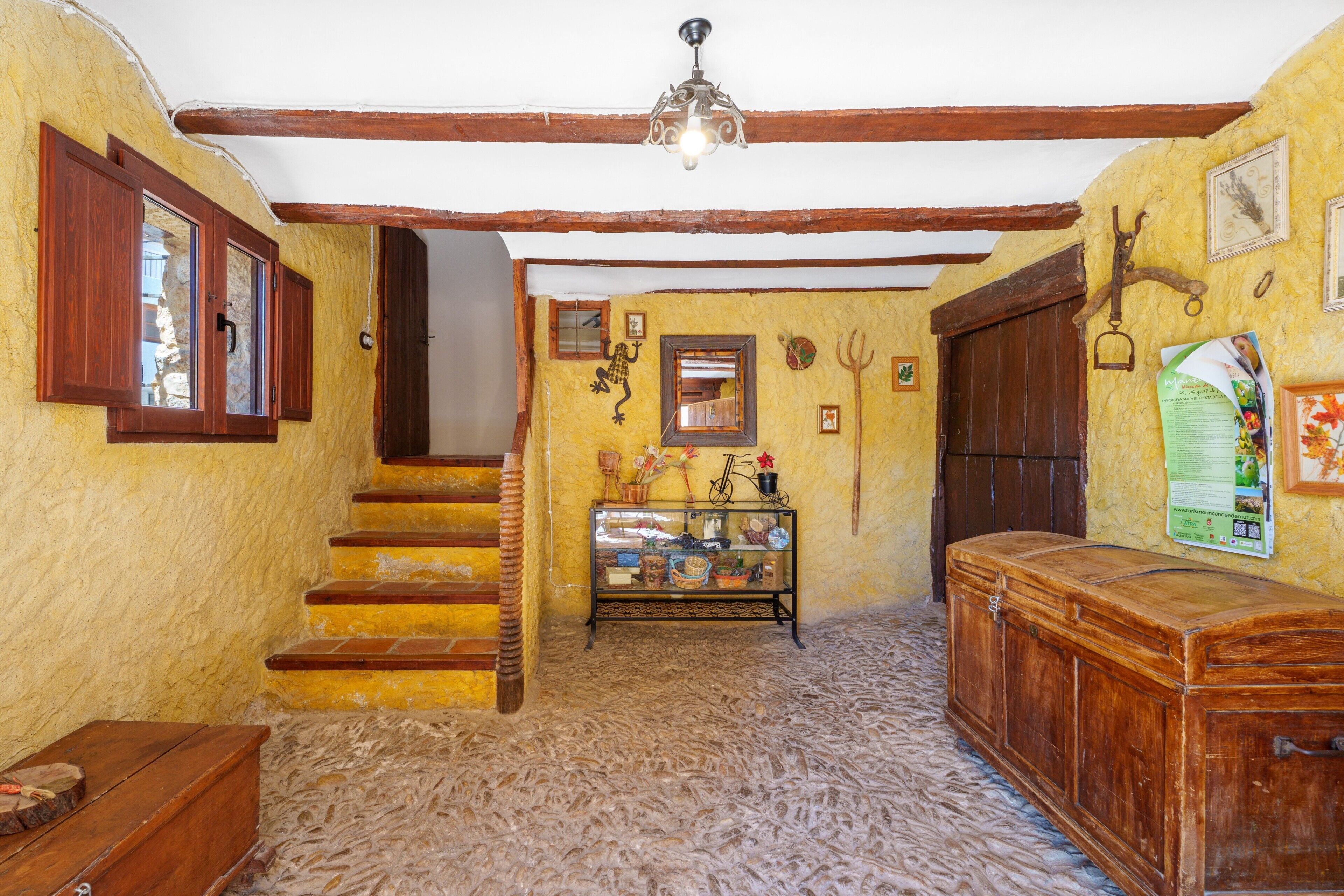 A rustic interior with wooden stairs, a display cabinet, and a wooden chest.