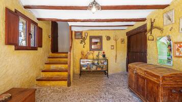 A rustic interior with wooden stairs, a display cabinet, and a wooden chest.