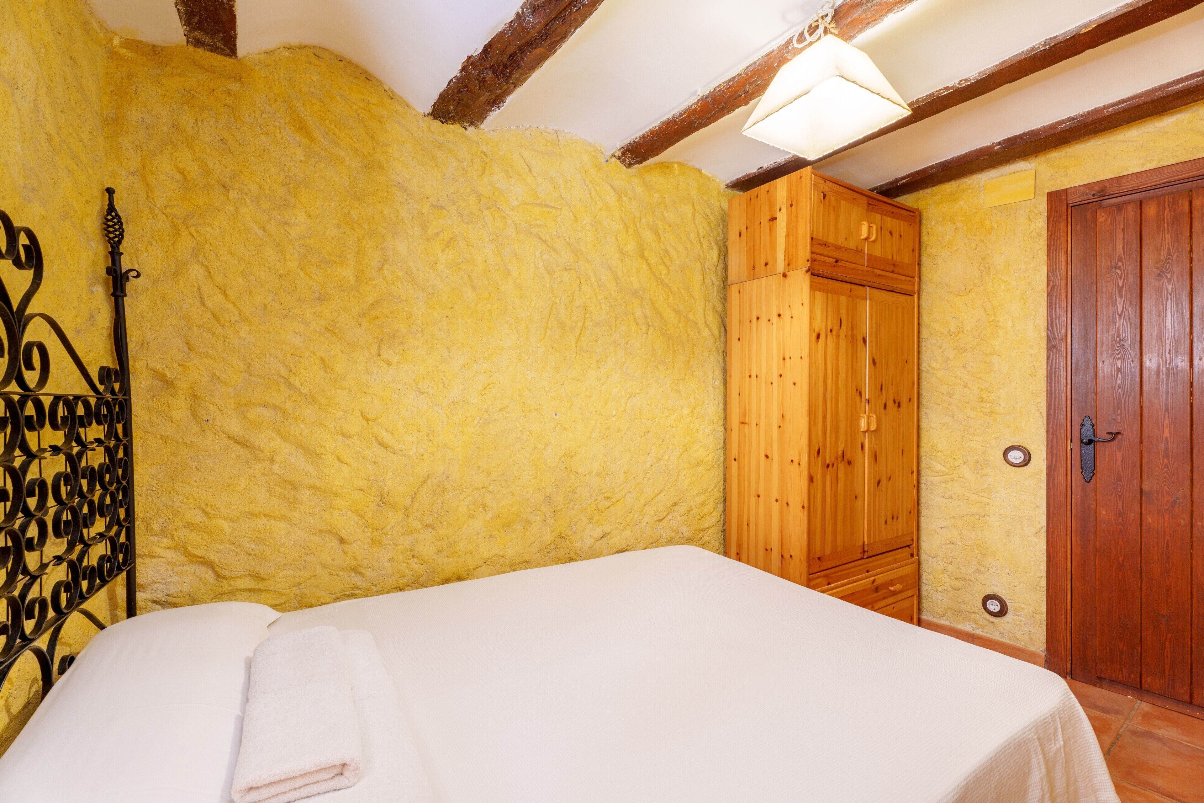 Una habitación con cama, armario de madera y una puerta.