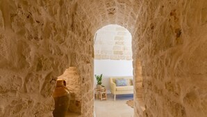 Un arco de piedra que da paso a una habitación con un sofá blanco, una mesita y una planta en maceta.