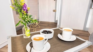 Une table avec deux tasses de café blanches, un petit bol de chocolat et un vase rempli de fleurs.