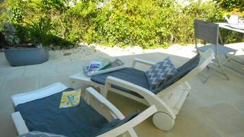 Two lounge chairs with cushions, a small table with a magazine, and a potted plant.