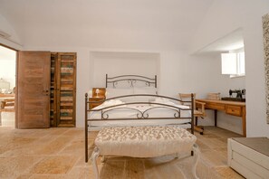 A bedroom with a bed, bench, wooden desk, and a mirror.