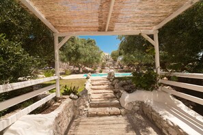 A stone pathway leading to a pool area under a pergola with white railings. - Villa 'Trullo Agapanthus with Panoramic' with Private Pool, Wi-Fi and Air Conditioning (Ostuni)