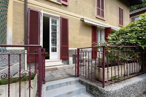 A building with a stone staircase, red shutters, and a metal railing.