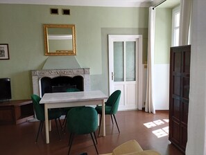 Un comedor con una mesa y sillas, una chimenea, una puerta con paneles de vidrio esmerilado y un espejo en la pared.