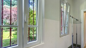 Una habitación con ventanas amplias, un perchero de metal y una puerta.
