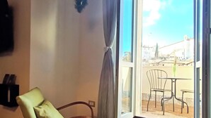 A room with a chair, a table, a curtain, and a view of the outside. - Monastero del Palazzo Casa Vacanze, apartment with panoramic terrace (Spoleto)