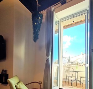 Une pièce avec une chaise, une table, un rideau et une vue sur l’extérieur.