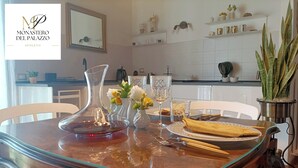 A dining table set with a clear glass pitcher, white vases with flowers, and a folded napkin. - Monastero del Palazzo Casa Vacanze, apartment with panoramic terrace (Spoleto)