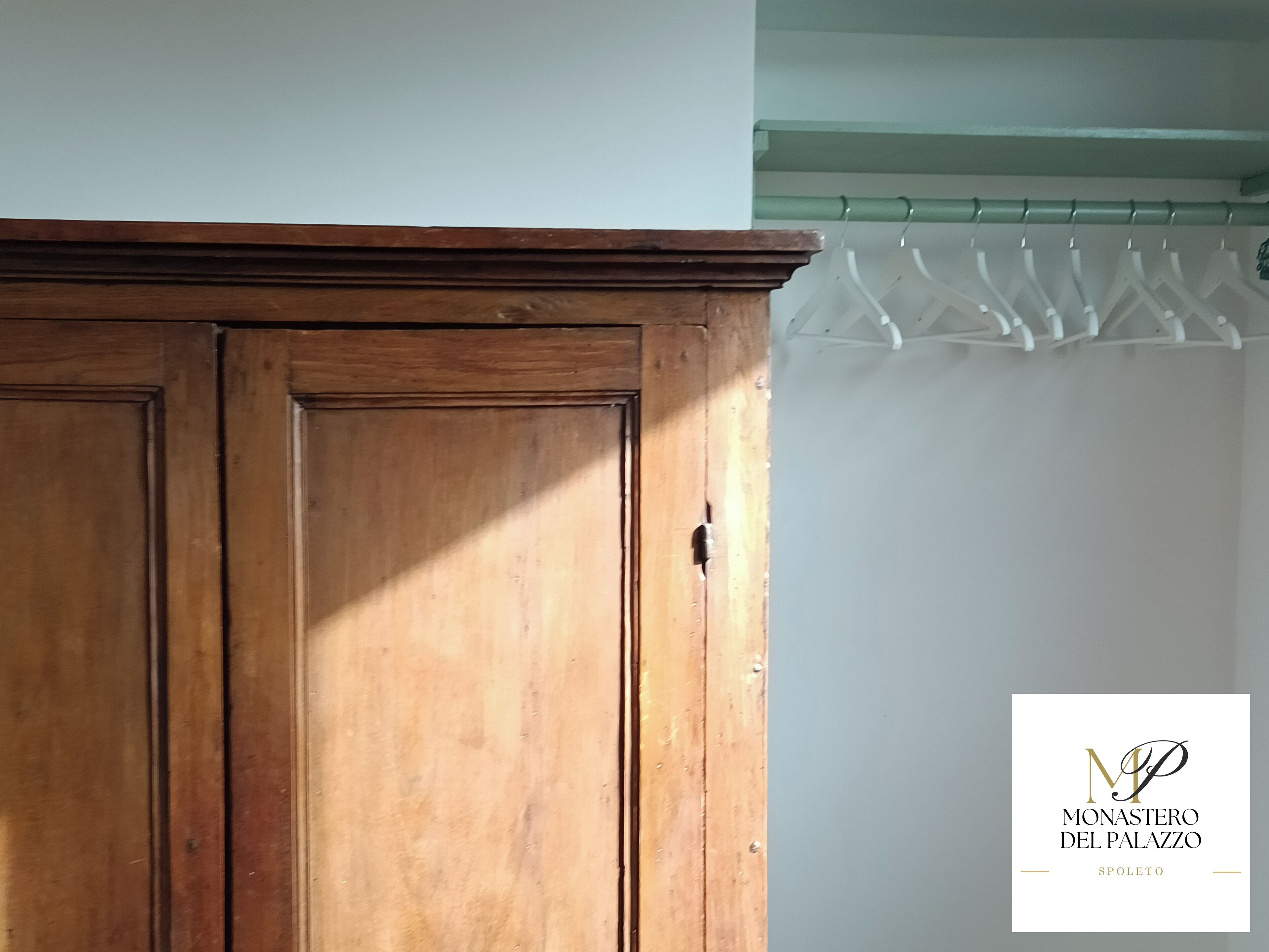 A wooden wardrobe with a handle, a white wall, and a curtain with a geometric pattern.