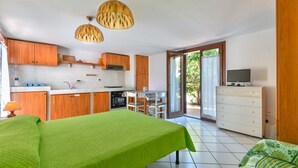 Una habitación con cama, una mesa de comedor, un televisor y una zona de cocina.