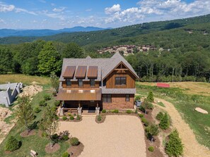A large wooden house with a sloped roof, multiple windows, and a well-maintained garden. - Bella Vista at Eagles Nest (Banner Elk)