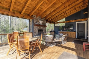 A wooden deck with outdoor furniture, a stone fireplace, and a TV. - A Robins Nest (Blowing Rock)