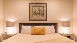 A neatly made bed with a white and yellow pillow, two bedside tables with lamps, and a framed picture on the wall. - A Robins Nest (Blowing Rock)
