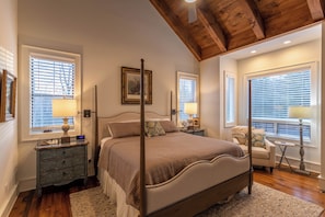 A bedroom with a four-poster bed, wooden beams on the ceiling, and multiple windows with blinds. - A Robins Nest (Blowing Rock)