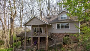 A two-story house with a balcony, a covered porch, and a staircase leading to the upper level. - A Treetop Escape (Blowing Rock)