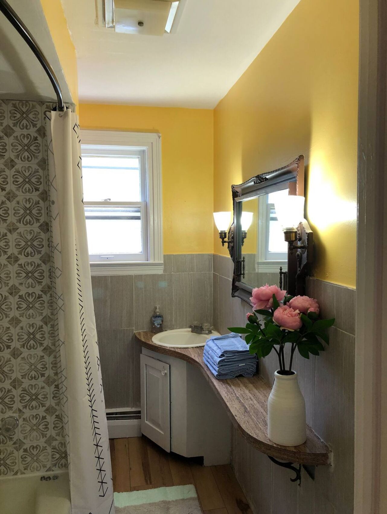 Une salle de bain avec un lavabo, un miroir et un rideau de douche.